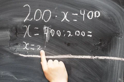 Boy standing back in front of school blackboard and writing. Schoolboy solves 스톡 사진