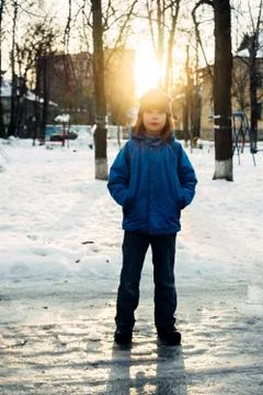 A boy standing in a blue jacket and hat in the backlight looking at the sky Stock Photos