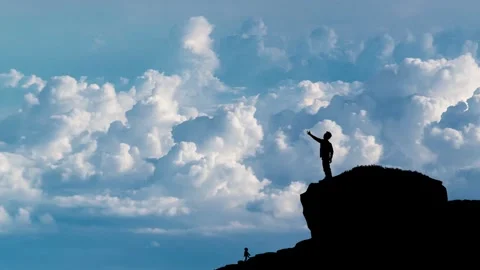 Boy standing on cliff pointing cloudy sky Stock Footage 259790790