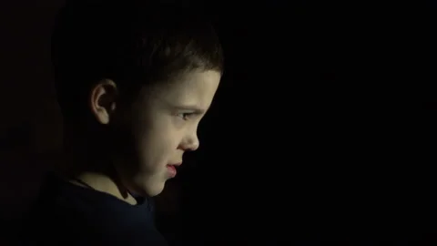 A boy is standing in the dark. Serious face. Flashing light 4K Stock Footage 126458273