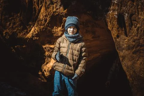 The boy is standing by the Devil's Cave in the nature park. Stock Photos