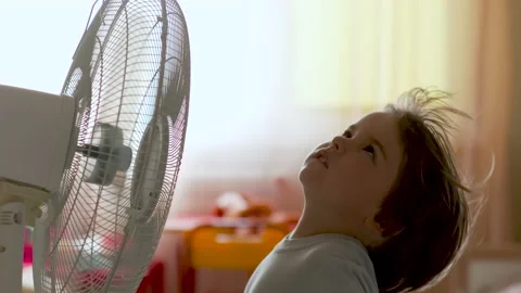 Boy Standing in Front of Fan. Child Enjoying Cool Wind From Electric Fan at H Stock Footage 134375840