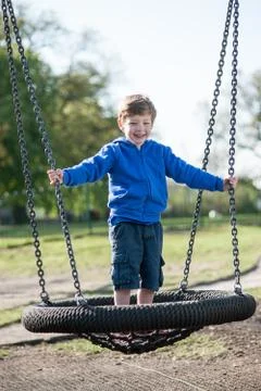 Boy standing on a large swing. Stock Photos