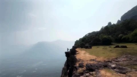 Boy Standing on the Last Stone at the Edge of the Mountain Stock Footage 287751063