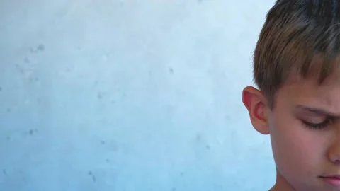 Boy standing lowered his head and looked down sadly. Half face. Child near Stock Footage 134474495