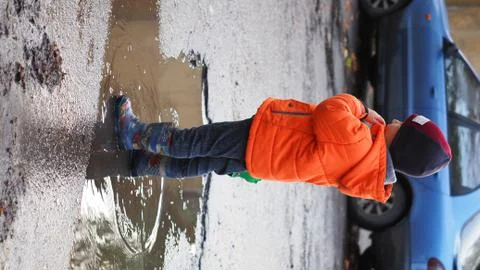 The boy is standing in a puddle in rubber boots Stock Photos