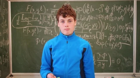 Boy standing with sponge in hand near blackboard and turning head. Stock Footage 69988265