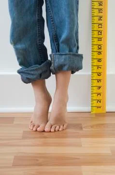 Boy standing on tiptoes next to ruler Stock Photos