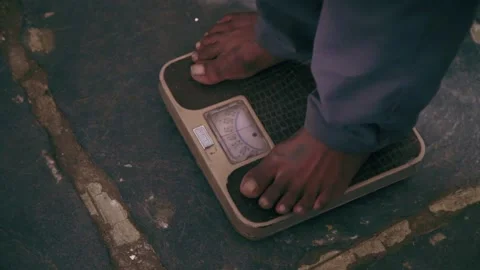 A boy standing on a weighing machine observes his weight Stock Footage 162077956