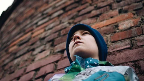 A boy stands against an authentic brick wall. Cool look. Beautiful frames. Stock Footage 128016561