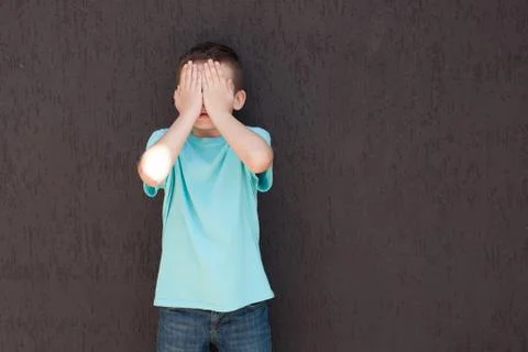 A boy  stands a  brown wall. Stock Photos