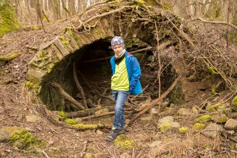 Boy stands in front of a cave during geocaching to look for a treasure Stock Photos