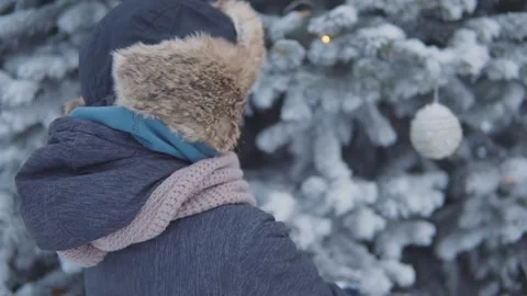 A boy stands in front of a snow-covered christmas tree Stock Footage 144727849