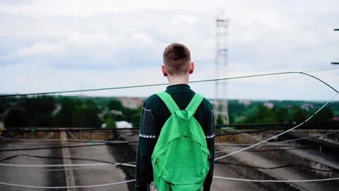 The boy stands in front of the wires strung on the roof of the house Stock Footage 132607111