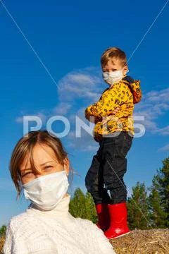 A boy stands on a haystack, his mother stands in front of him Stock Photos