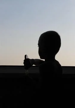 Boy stands at the open window, summer at sunset Stock Photos