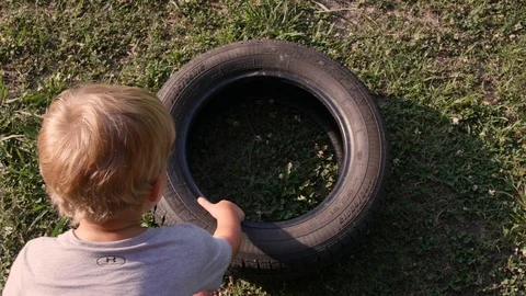 Boy stands tire on end and rolls it away Video stock 98917573