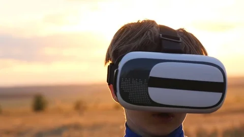 A boy stands in a wheat field at sunset in virtual glasses Stock-Footage 77706955