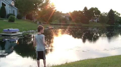 Boy Staring at Calm Water at Sunset Video stock 65745494