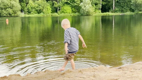 A boy steps into water at Kolonistsky Pond Beach in Pushkin Video stock 344987522