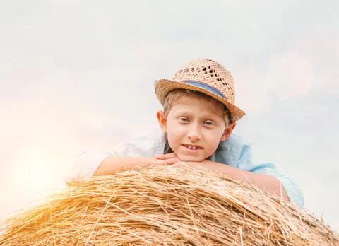 Boy in straw hat lying on the haystack Foto stock