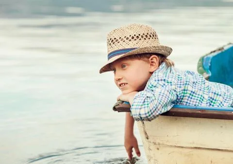 Boy in straw hat lying in old boat Stock Photos