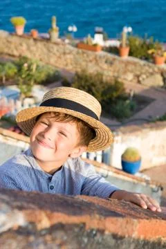 Boy in straw hat smiles against sea Stock Photos