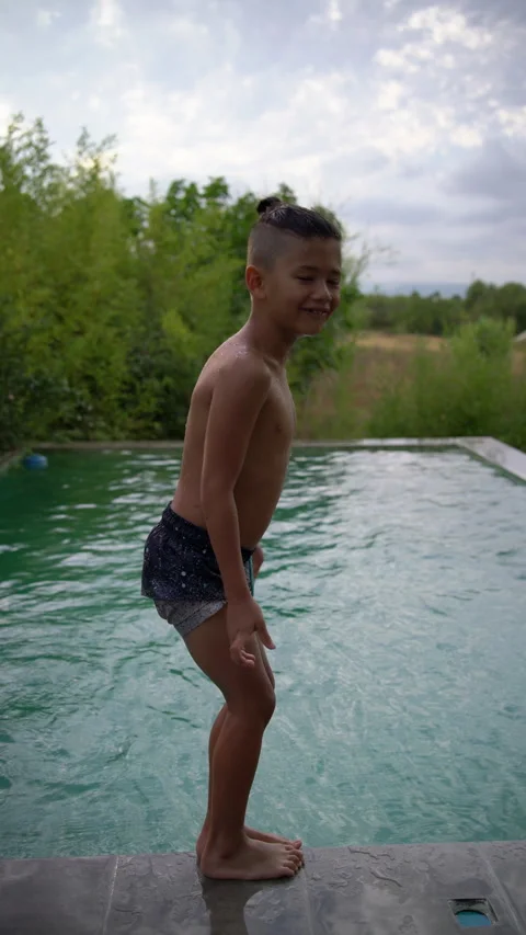 Boy Strikes a Playful Pose on Pool Edge Before Jumping In 스톡 동영상 345043612