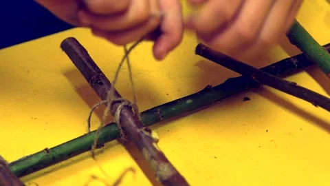 Boy with String Ties Knots, Ties Branches, Makes a Decoration Stock Footage 257973022