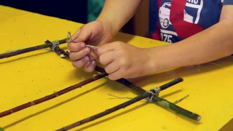 Boy with String Ties Knots, Ties Branches, Makes a Decoration Stock Footage 257973025