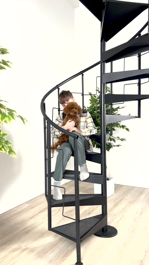 Boy stroking a small brown poodle on head and chest on a spiral staircase in a Stock Footage 273818286