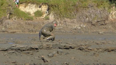 A boy struggles in the mud, falling down, during a fun run competition, Vidéo 106743872