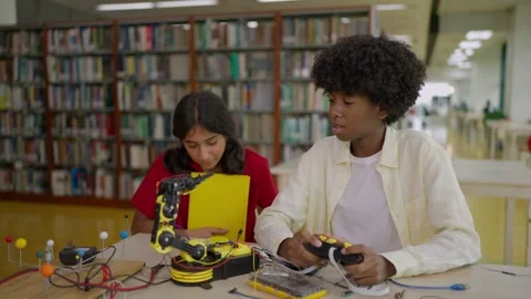 Boy student explaining a robotic arm to female friend to operate the technology. Stock Footage 326640730
