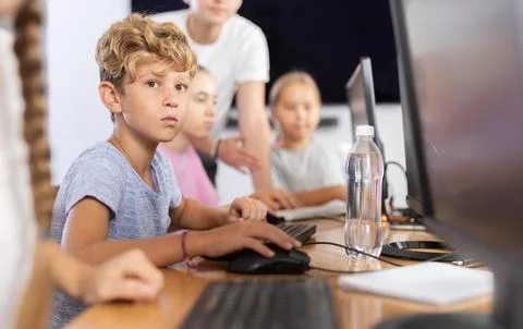 Boy student learning to work on computer in classroom Stock Photos