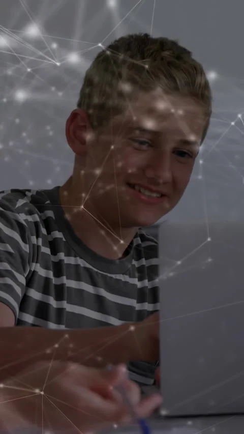 Boy student reaching for off-frame pen then returning to laptop while network Stock Footage 330794792