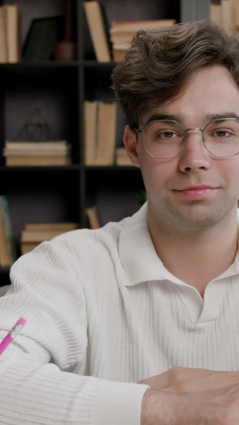 A boy student sitting on a bench in a classroom looks directly at the camera Stock Footage 318216392