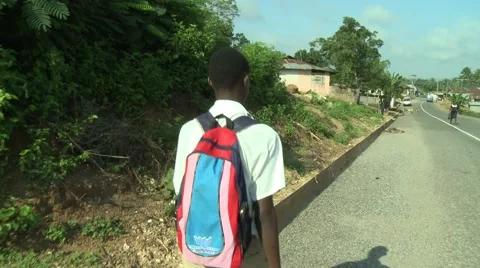 BOY STUDENT WEARING BACKPACK WALKS DOWN STREET Stock Footage 58930380