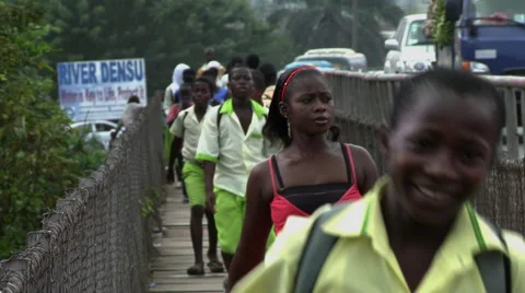 BOY STUDENTS RUN ACROSS BRIDGE OVER DENSU RIVER TOWARDS CAMERA Stock Footage 58106413