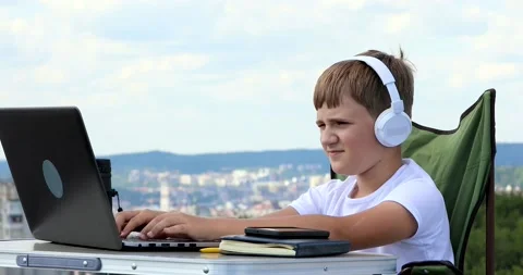 The boy studies at the computer in headphones, and turns on the music on the  Stock Footage 136541647