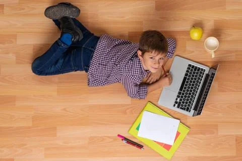 Boy studies lying on the floor with computer Stock Photos