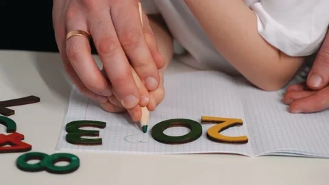 The boy studies numbers, draws and writes numbers, rejoices in success. Dad Stock Footage 230669384