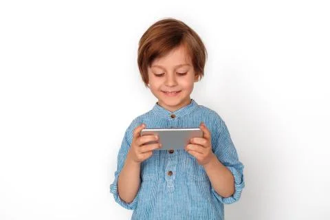 Boy studio standing isolated on grey playing game on smartphone happy Stock Photos