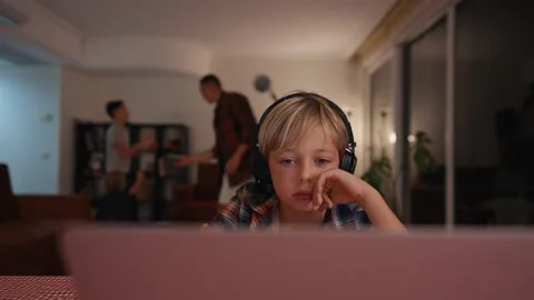 Boy study at home. Boy study on laptop with family playing around. Family Stock Footage 224165326