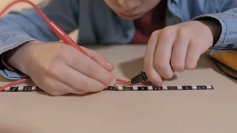 The boy studying electronics. Uses a digital multimeter and led strip Stock Footage 130108244