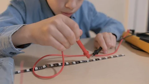 The boy studying electronics. Uses a digital multimeter and led strip Stock Footage 130108246