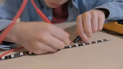 The boy studying electronics. Uses a digital multimeter and led strip Stock Footage 130108247