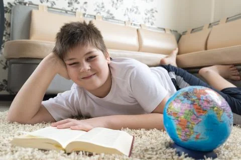 Boy studying the globe and reading  book Stock Photos