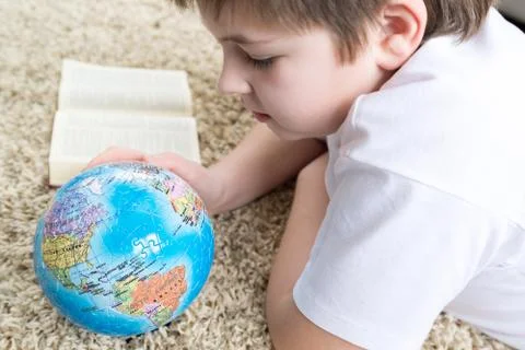 Boy studying the globe and reading  book Stock Photos
