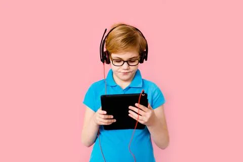 Boy studying homework with tablet pc and earphones during his online lesson.. Stock Photos