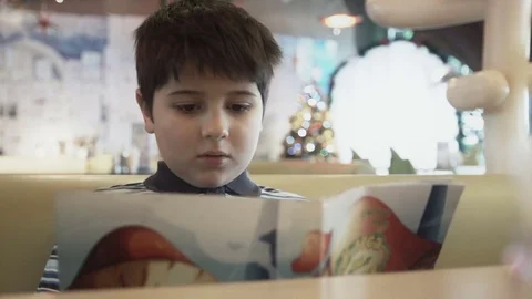 The boy is studying the menu in the New Year's cafe Stock Footage 76727864